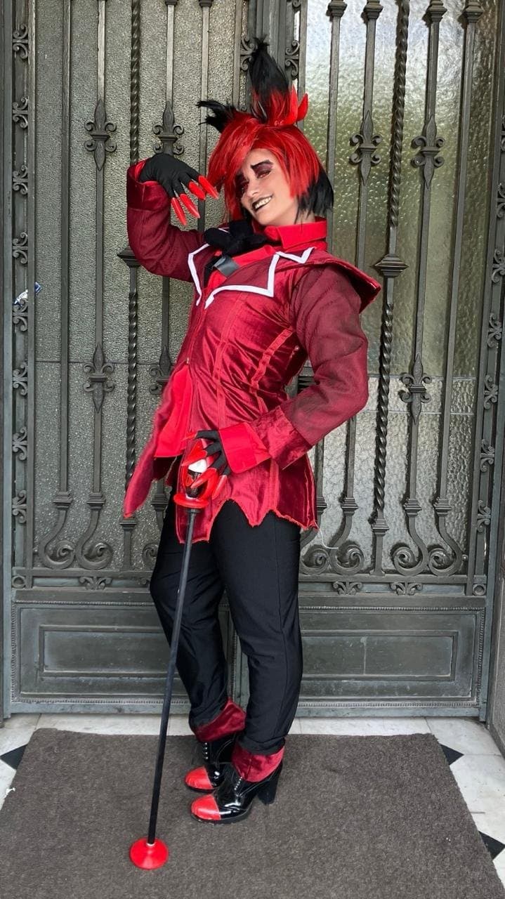 Alastor Cosplay caracterizadx como Alastor, el Demonio de la Radio de Hazbin Hotel, con traje rojo y bastón micrófono